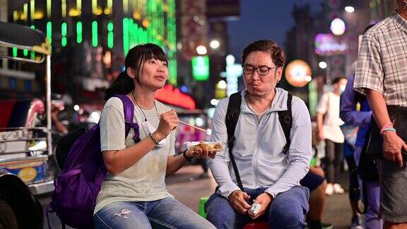 4K亚洲夫妇喜欢在曼谷Yaowarat路交通拥挤的街头吃食物