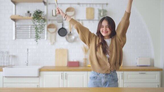 亚洲年轻女子在厨房跳舞她在周末的空闲时间快乐和放松