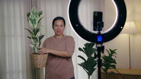 亚洲女性用智能手机在线直播在家里卖人造植物