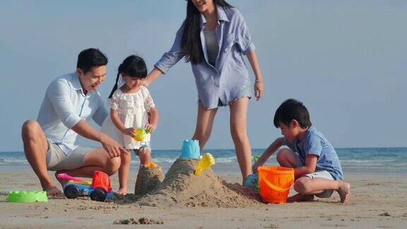 一家人在沙滩上的沙箱里为孩子们玩玩具快乐的一家人在海滩上享受暑假假期iStock