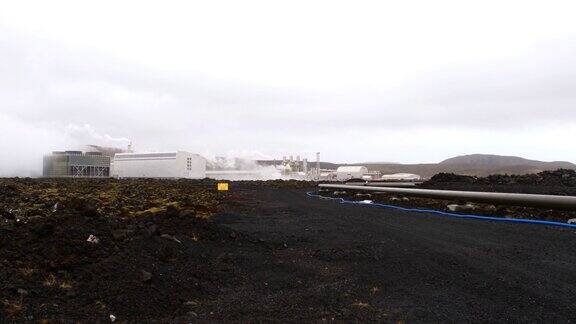冰岛Grindavík附近的地热电站Svartsengi阴天冒着热气的烟囱和苔藓覆盖的熔岩田旁边的警告标志