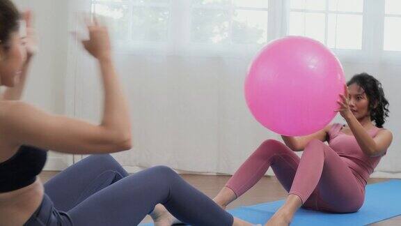 年轻漂亮的女人在客厅锻炼她在家一起用运动球锻炼身体生活方式运动和瑜伽