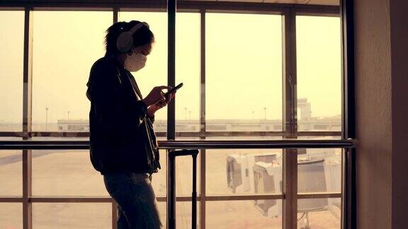 亚洲女性戴着口罩在机场候机区使用数码平板电脑