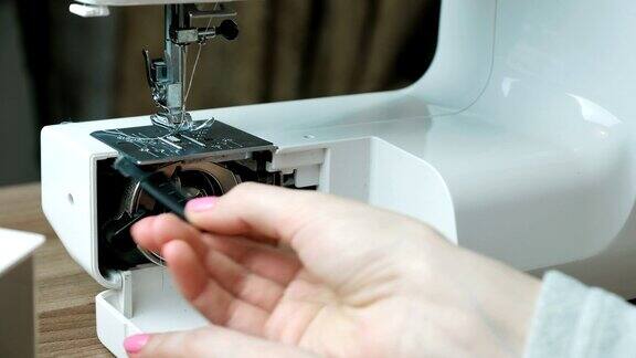 女人打开缝纫机用刷子把里面的灰尘擦干净