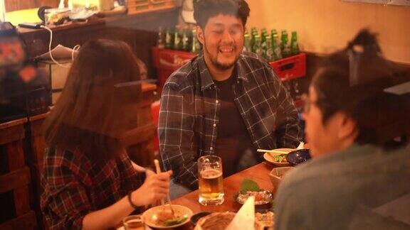 亚洲夫妇和朋友在日本居酒屋餐厅酒吧吃和喝啤酒