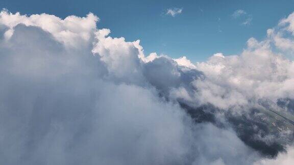 山脉从下面的云层中飞过低云覆盖下的空中飞行天气变化全球变暖鸟瞰图