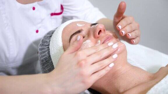 美容师在女性脸上涂抹护肤霜