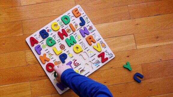 小男孩把字母拼图和学习英语放在地板上