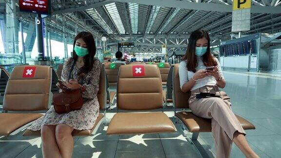 两名年轻的亚洲女性在机场使用智能手机