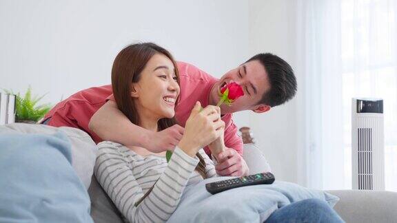 亚洲青年惊喜送玫瑰给美丽的女友迷人浪漫的新婚男女花时间在房子里一起庆祝周年纪念日和情人节