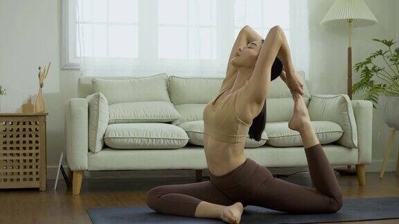 美丽的亚洲女人在家里做瑜伽女性在家锻炼