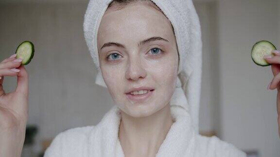 年轻女子穿着浴袍头上裹着毛巾用黄瓜遮住眼睛