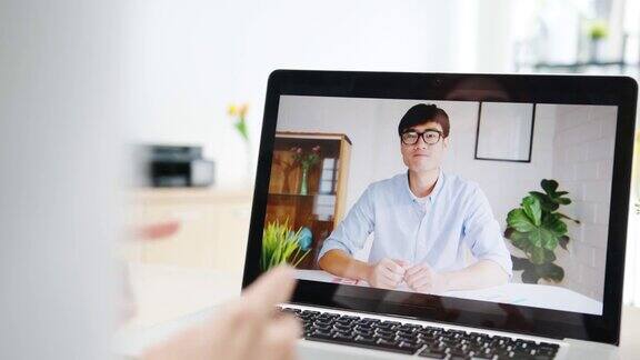 亚洲女商人使用笔记本电脑与同事在视频电话会议的计划而工作在家里的客厅