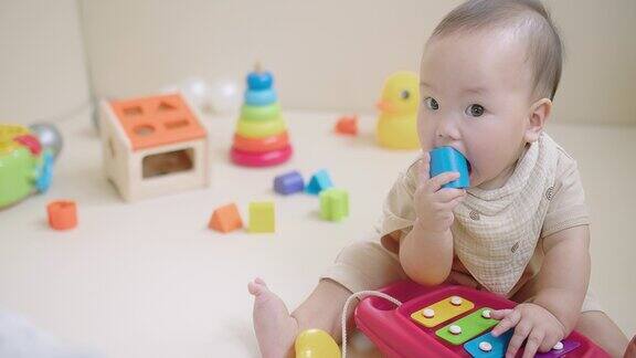 可爱的快乐的小亚洲婴儿的肖像幼儿玩彩色玩具在地板上的客厅教育游戏的婴儿和幼儿