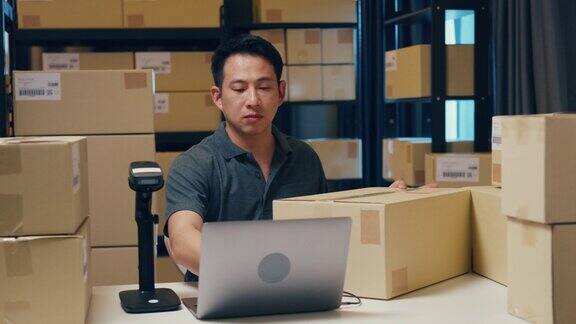 亚洲商人使用条码机扫描纸盒中的客户数据并在笔记本电脑上输入注册在线信息订单明细以便在仓库发送快递