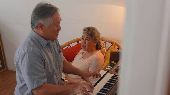 4K亚洲老夫妇一起在家里的客厅里弹钢琴和唱歌