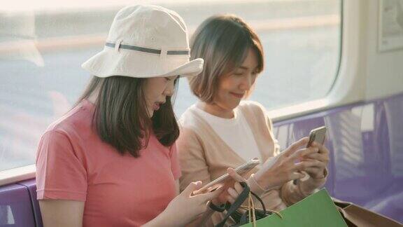 两个亚洲女人在火车上使用智能手机聊天慢动作