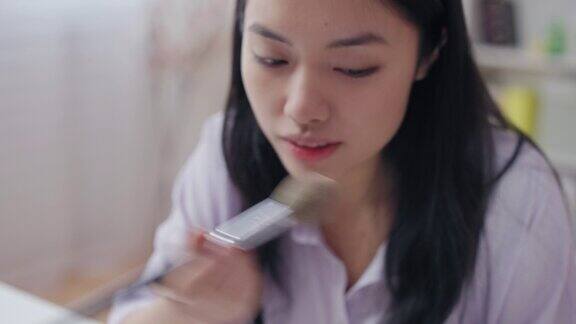年轻的亚洲女性应用化妆皮肤化妆品无残忍