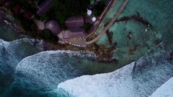 马尔代夫岛的顶视图摄像机下到酒吧在豪华热带酒店度假一架无人机从餐厅上空降落上面显示出巨大的海浪飞溅的航拍画面