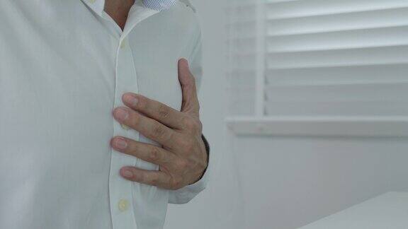 手握胸脯有心脏病发作的症状亚洲人工作辛苦有胸痛引起的心脏病漏、扩张、冠状动脉增大压在胸口有疼痛的表情