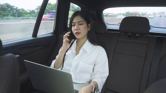女商人在车里与客户和合伙人通电话她正在用笔记本电脑做笔记写下有用的信息
