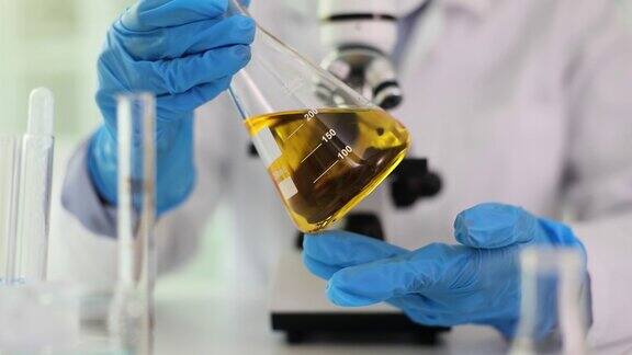 化学实验室技术员手持装有黄色液体的烧瓶
