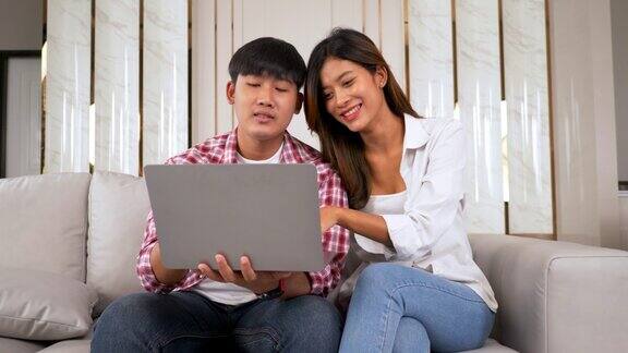 迷人的年轻夫妇用笔记本电脑和朋友聊天