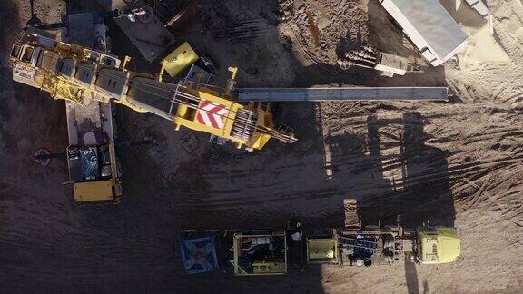 在一个阳光明媚的日子里一架无人机在山谷里的一个石油和天然气钻井平台上直接拍摄了起重机拆卸钻机的画面