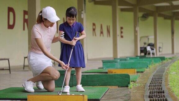 亚洲华人妈妈在高尔夫球场教女儿打高尔夫球