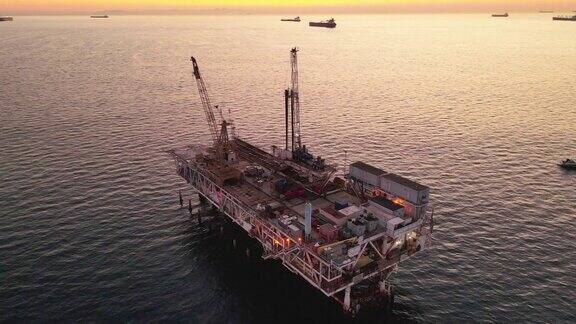 灯火通明的海上石油和天然气钻井平台在一个晴朗的夜晚在加州长滩洛杉矶附近的黄昏远处有货船