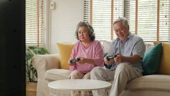 亚洲老年夫妇在家里一起玩游戏心情愉快人们以放松、养老、退休、高级生活方式为家庭观念