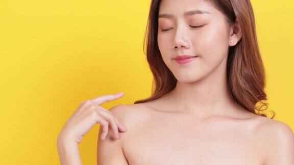皮肤护理肖像摆亚洲美女手摸脸和肩膀与黄色背景工作室拍摄