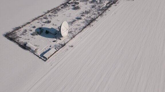 在晴朗的冬日无人机在战略目标上空飞行白雪覆盖的空间通信站鸟瞰图