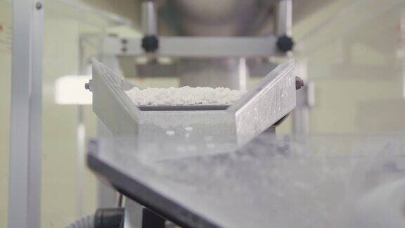分批分拣的药片落在自动包装机上制药厂的药品生产化学工业