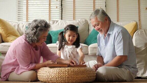 一对亚洲老夫妇在家里和一个小女孩一起玩高级生活方式家庭理念