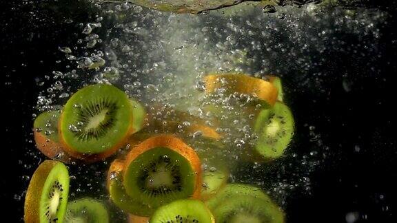 新鲜猕猴桃片落入飞溅的水中的超慢动作新鲜果汁烹饪概念拍摄于高速影院摄像机4k1000fps