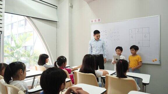 亚洲小男孩建议一起思考数学答案的方法老师在学校的教室里教孩子们教育理念、经验学习和技能发展