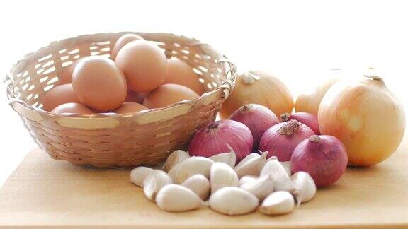 鸡蛋、洋葱和大蒜放在木桌上