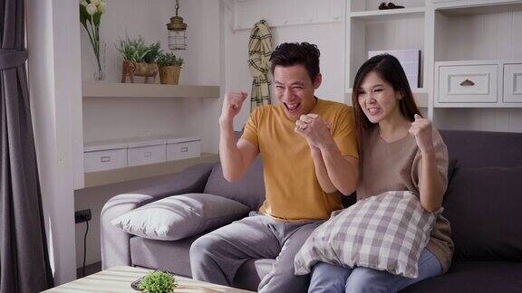 年轻的亚洲幸福夫妇在客厅的沙发上看电视夫妇放松和一起在家里度过时间