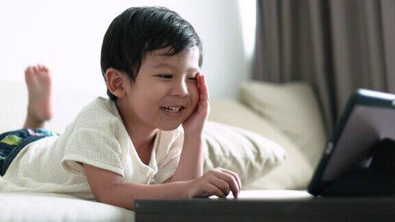 微笑的亚洲男孩在家里用平板电脑看东西