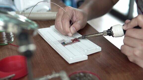 工人用手将一个元件焊接到电路板上