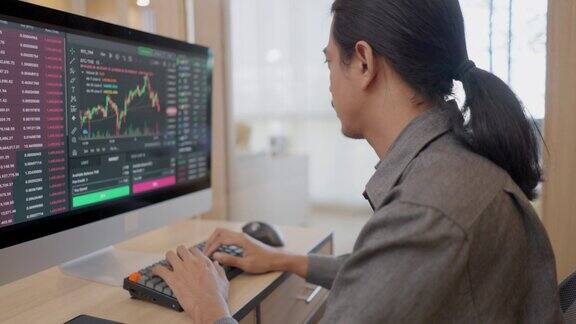 亚洲专业金融支持专家的侧视图通过办公室的电脑查看网上股票市场的交易价格并在电脑屏幕上显示股票市场交易图表股票交易员