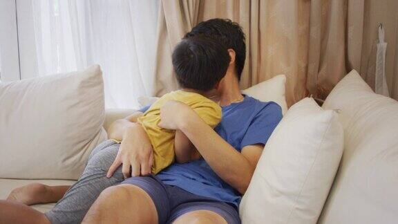 父亲和年幼的儿子在家里的沙发上拥抱