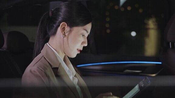 一个女人在城市灯光下在车里玩平板电脑