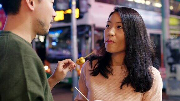 SLOMO手持中景拍摄一对年轻夫妇在香港街头吃小吃