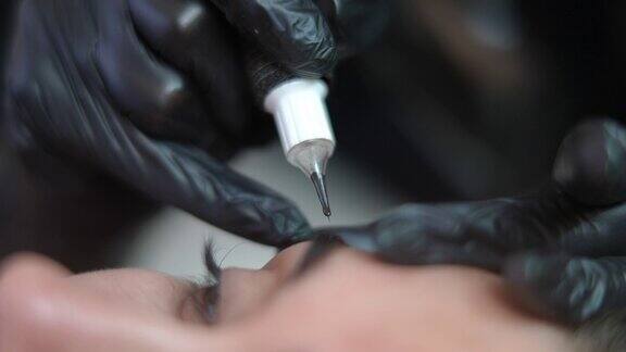 特写纹身大师的手使用微刀片笔注入墨水在眉毛皮肤的年轻白人妇女客户在美容院做定妆微刀纹