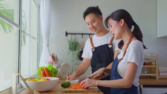 亚洲新婚夫妇待在家里在厨房共度时光浪漫年轻英俊的夫妇享受周末准备材料在家做饭家庭活动的关系
