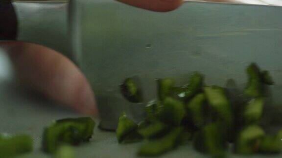 一位年长的白人妇女用菜刀在切菜板上切着波布拉诺辣椒