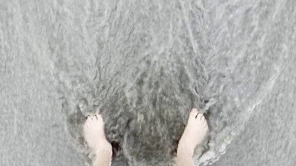 高角度4K视图的人的脚与海浪在约克缅因州长沙海滩的岸边