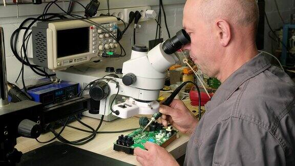 电子设备修理店工程师技术员在显微镜下焊接电子设备的印刷电路板
